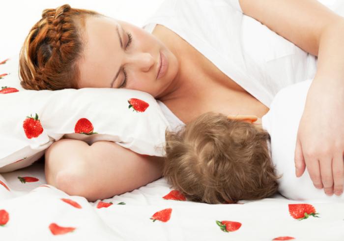 Mother breastfeeding her baby while bed-sharing