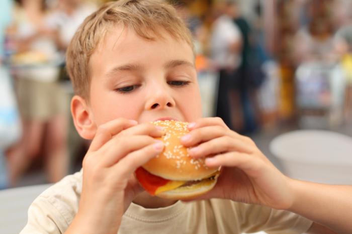 A young boy eating a burger