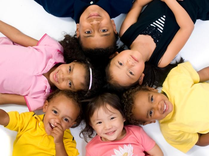 Children lying down in a circle smiling.